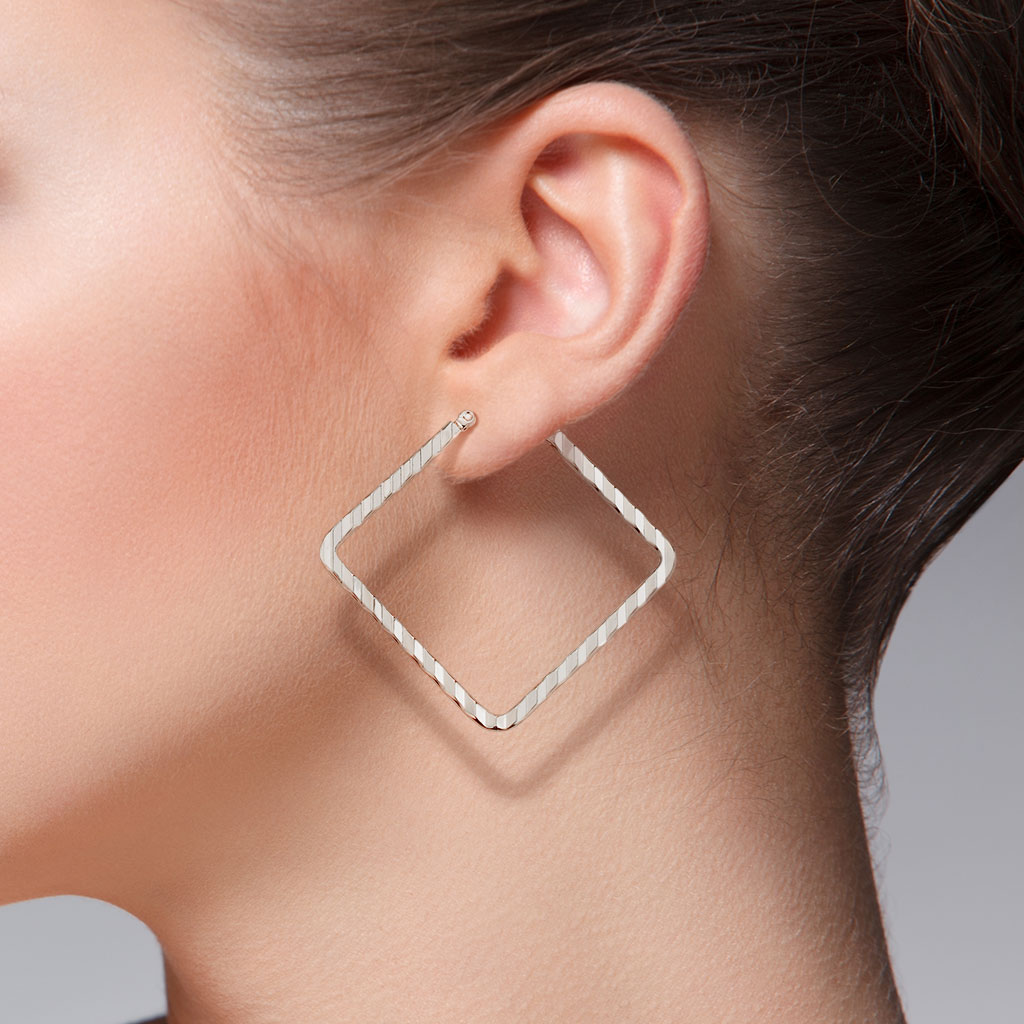 Portrait d'une jeune femme portant des boucles d'oreille créole géométriques de forme carrée