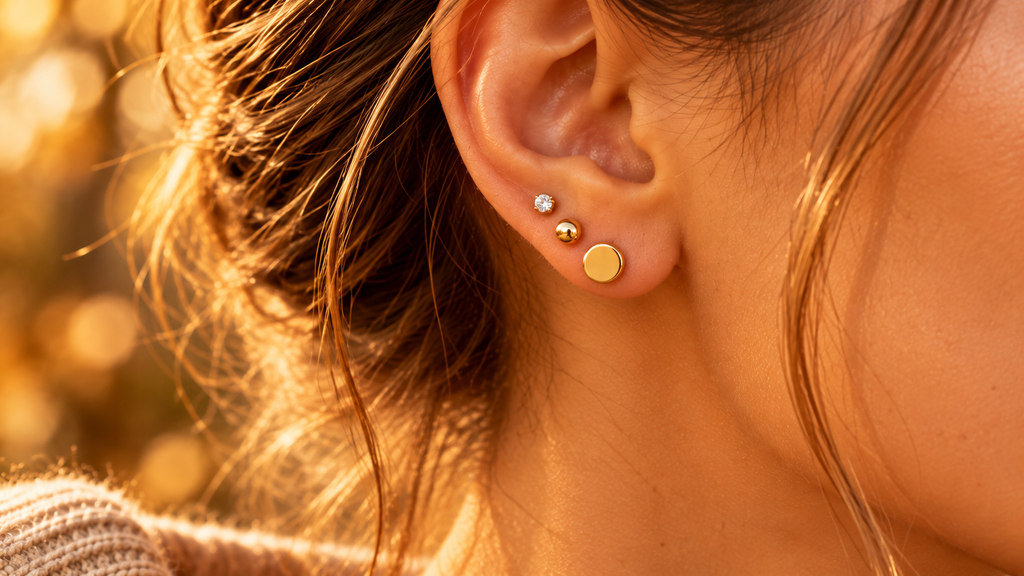Ear stacking de studs dorés sur lobe — tendance piercing automne 2026
